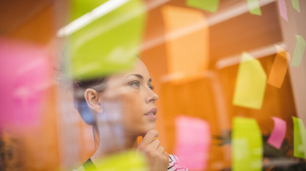 Vrouw bestudeert muur met memo-blaadjes