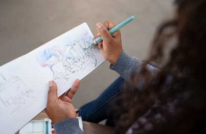 Vrouw tekent een stad in een schetsboekje