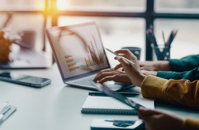 Twee personen wijzen naar een scherm waarop grafieken te zien zijn.