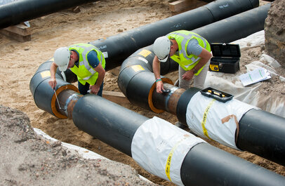 Twee personen zijn bezig met de aanleg van een warmtenet