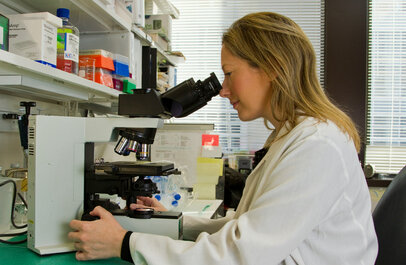 Wetenschapper kijkt in microscoop