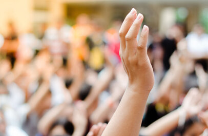 Opgestoken hand uit een menigte mensen