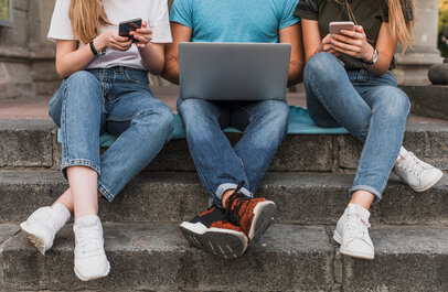 Drie jongeren in de weer met gsm en laptop