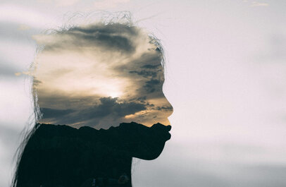 Silhouette van een vrouw, in het silhouette is een bewolkte lucht te zien