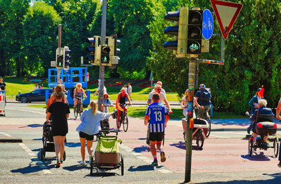Kruispunt nabij een park, verschillende fietsers en voetgangers steken over