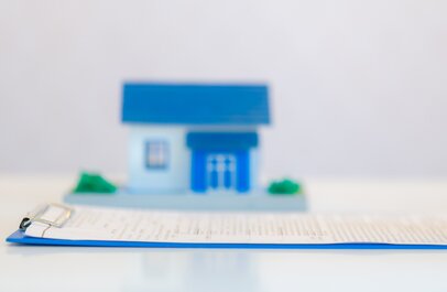Iemand vult een formulier in, op de achtergrond staat een huisje