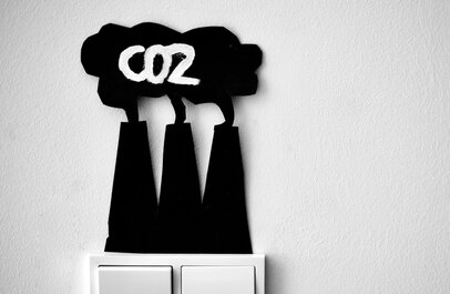 schakelaars met daarboven pictogram van Co2 uitstoot uit schoorstenen