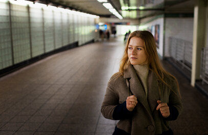 Vrouw alleen in een metrostation, kijkt wantrouwend om zich heen