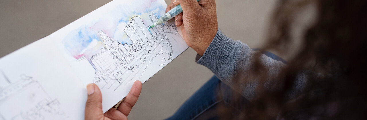 Vrouw tekent een stad in een schetsboekje