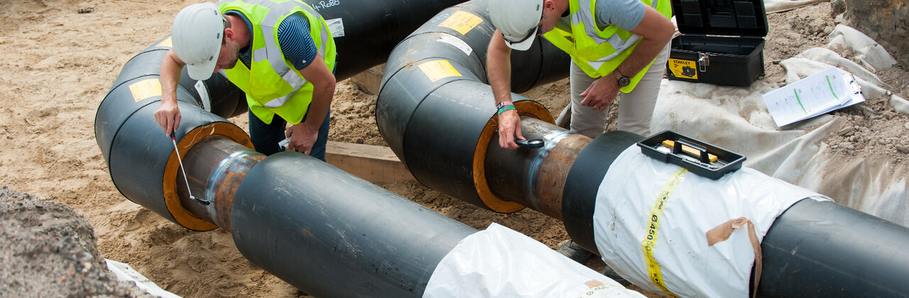 Twee personen zijn bezig met de aanleg van een warmtenet