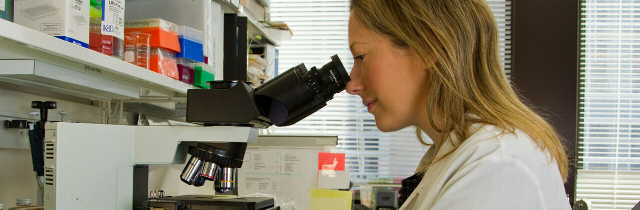 Wetenschapper kijkt in microscoop