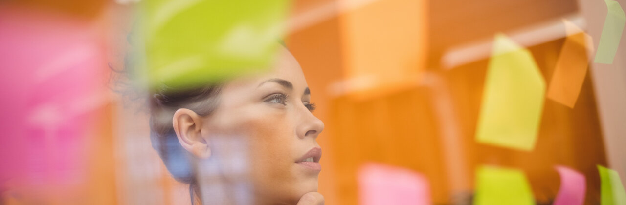 Vrouw bestudeert muur met memo-blaadjes