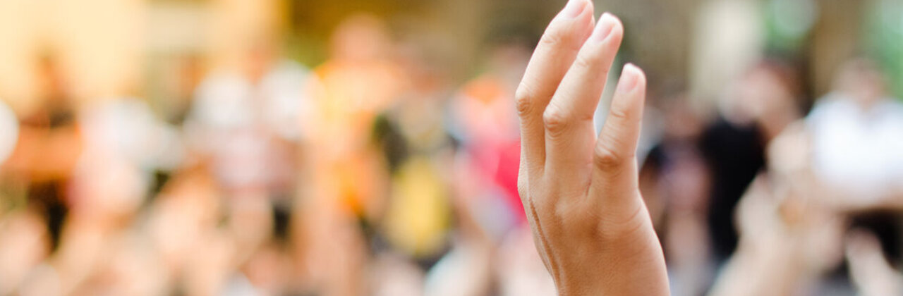 Opgestoken hand uit een menigte mensen
