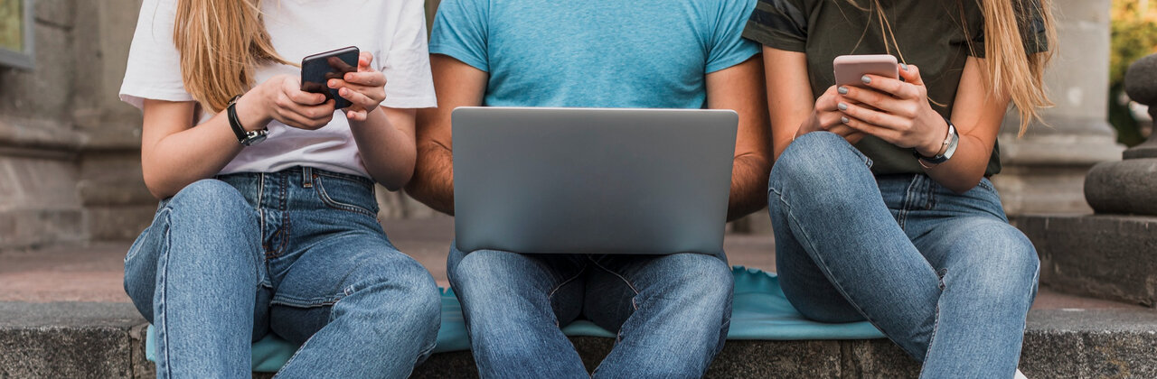 Drie jongeren in de weer met gsm en laptop