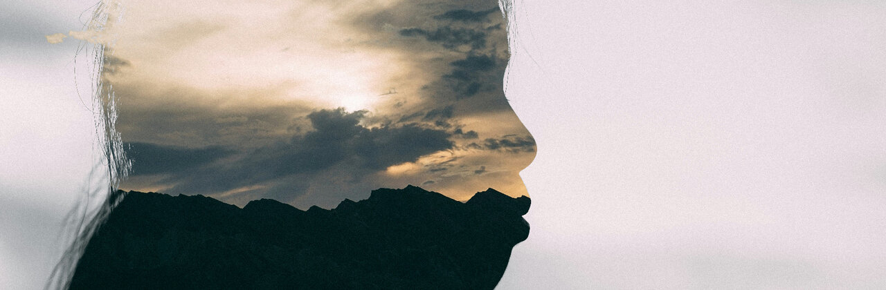 Silhouette van een vrouw, in het silhouette is een bewolkte lucht te zien