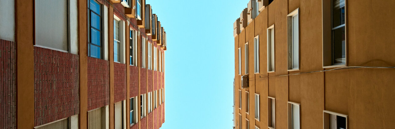 Twee hoge flatgebouwen van onderaf gefotografeerd