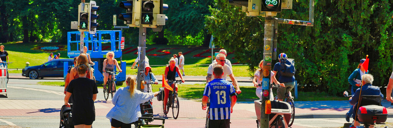 Kruispunt nabij een park, verschillende fietsers en voetgangers steken over
