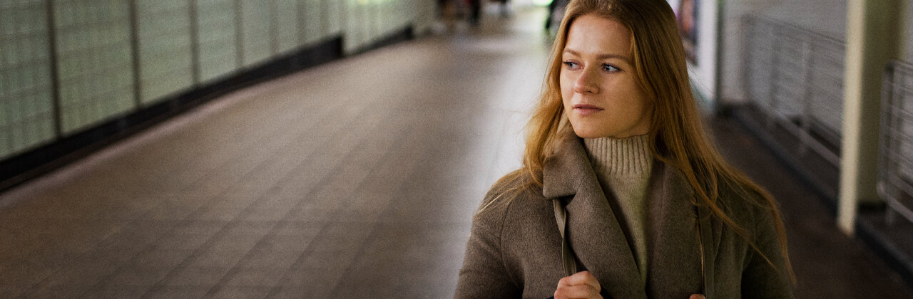 Vrouw alleen in een metrostation, kijkt wantrouwend om zich heen